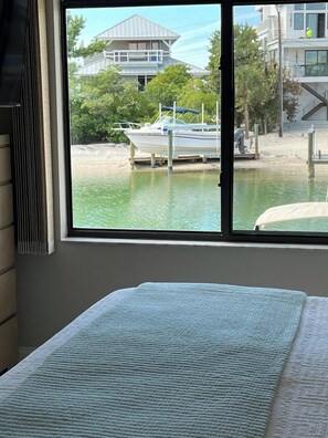 A bedroom with a large window overlooking a dock and a building. - Waterfront Siesta Key • Community Dock • Near Beach & Dining • 30 Night Minimum (Sarasota)