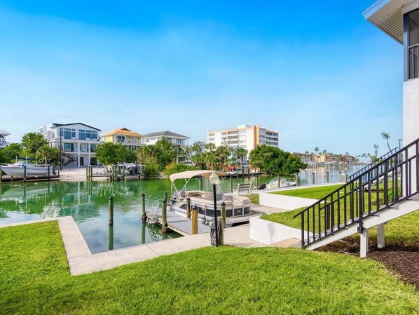 A marina with boats docked, a grassy area, and buildings in the background. - Waterfront Siesta Key • Community Dock • Near Beach & Dining • 30 Night Minimum (Sarasota)