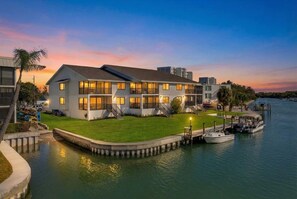 A waterfront property with a large house featuring multiple balconies, a dock with boats, and a grassy lawn. - Waterfront Siesta Key • Community Dock • Near Beach & Dining • 30 Night Minimum (Sarasota)