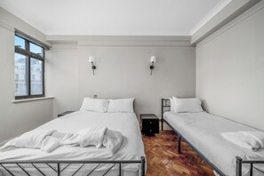 Een kamer met twee bedden, een raam en een lamp aan de muur.
