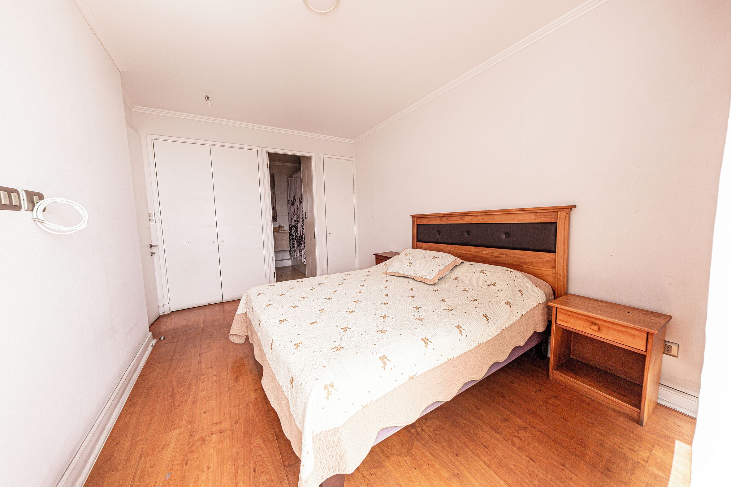 Un dormitorio con una cama de madera, una mesita de noche y un armario.
