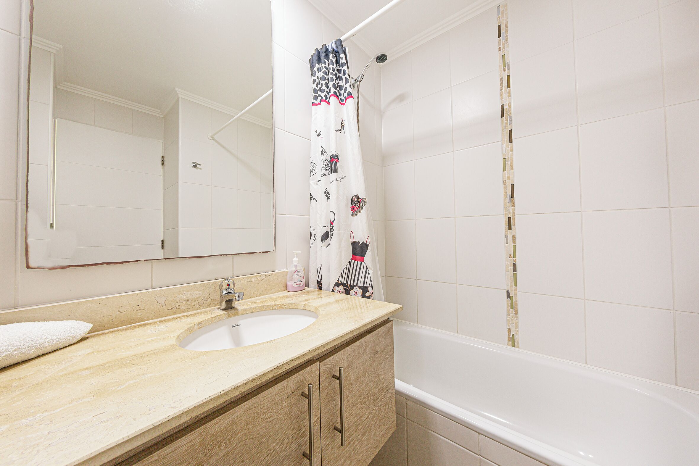 A bathroom with a sink, mirror, and shower curtain.