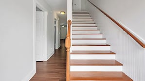 Een trap met houten treden en een houten leuning, die naar een deur aan de bovenkant leidt.