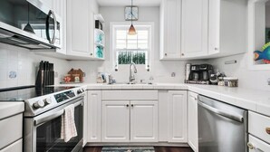 Een moderne keuken met witte kasten, roestvrijstalen apparatuur en een houten vloer.