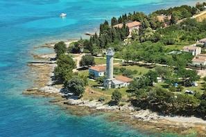 A coastal property with a lighthouse, clear blue waters, and a mix of residential and natural areas. - Elia Apartments 2 Complete apartment with private garden (Savudrija)