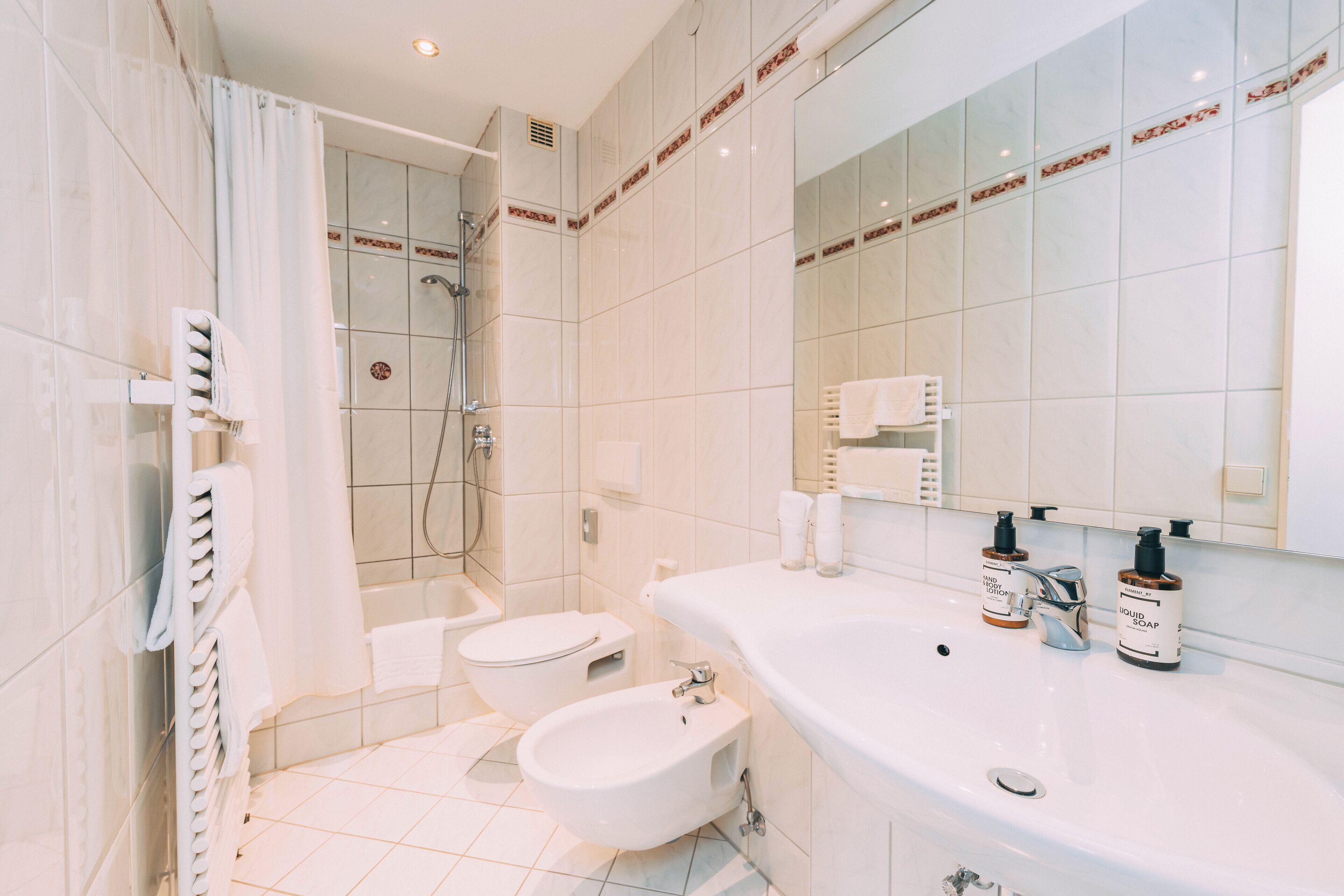 Et moderne badeværelse med bruser, toilet, bidet og håndvask.