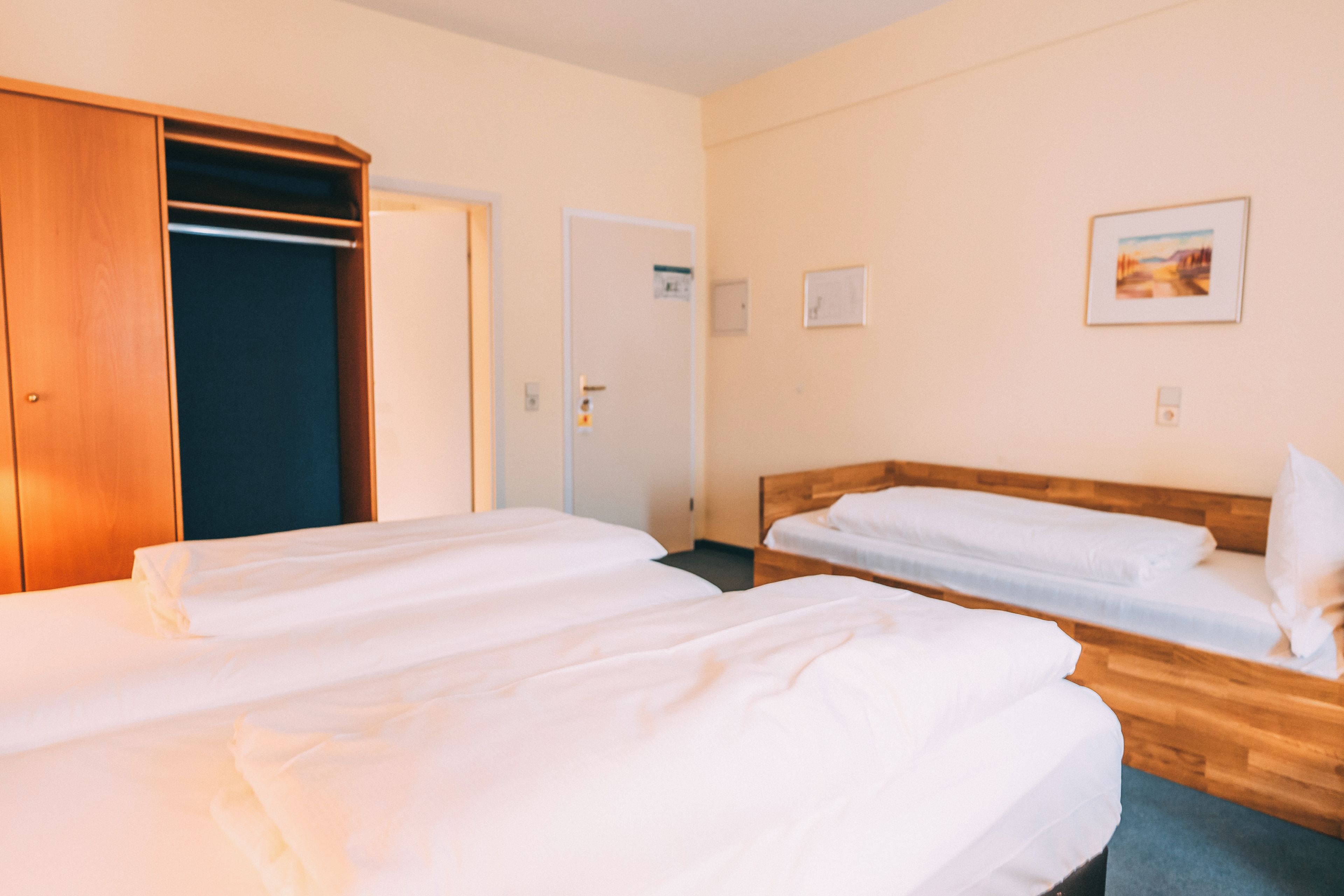 A hotel room with two beds, a wardrobe, and a door.