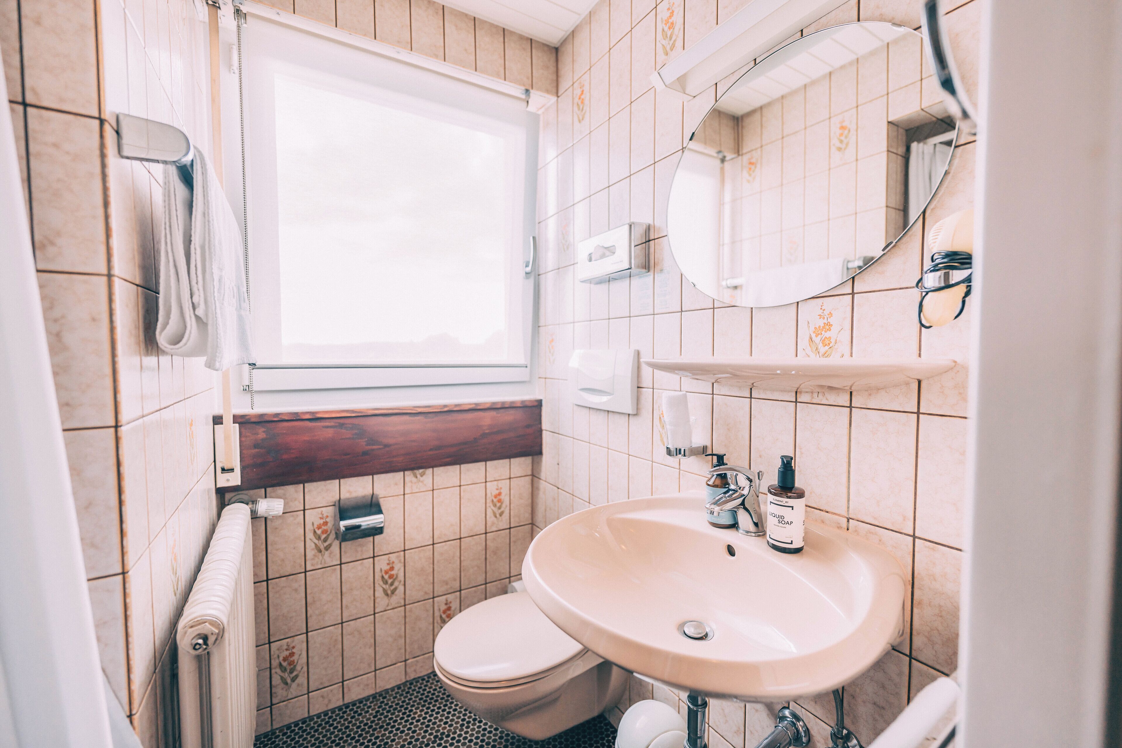 A bathroom with a toilet, sink, and mirror.