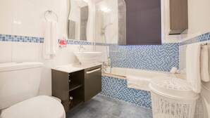 A bathroom with a toilet, sink, mirror, shower, and a laundry basket. - BELAIR (St. Julian's)