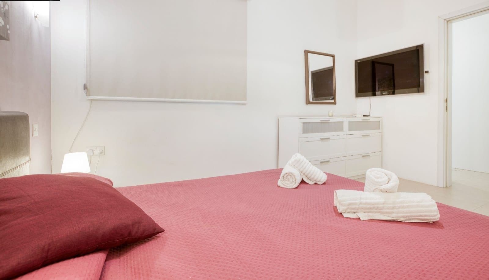 Una habitación de hotel con cama, cómoda, espejo y toallas.