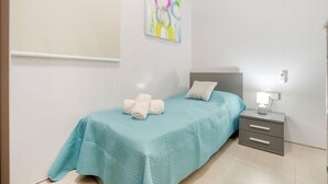 A bedroom with a bed, a nightstand, a lamp, and a painting on the wall. - BELAIR (St. Julian's)