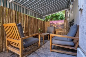 An outdoor seating area with wooden furniture and a bamboo fence. - Ehad Ha'am Haifa Urban Design Suite by Shay’s Urban (Haifa)