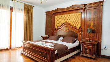 A bedroom with a large bed, wooden headboard, bedside tables, and a chandelier.