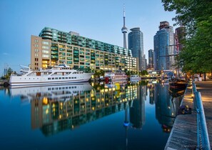 A waterfront hotel with a large glass facade, a prominent tower, and a reflection in the water. - Bright & Modern Downtown Condo, Walk to Jays & MTCC (Toronto)