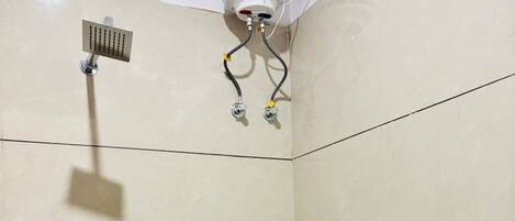 A corner bathroom with a shower, a toilet, and a bucket.