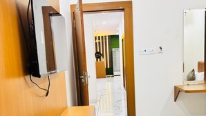 Une chambre d’hôtel avec un banc en bois, un téléviseur fixé au mur, un lit et un sol en marbre.