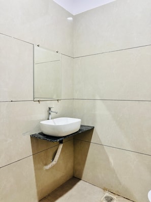 Un bagno con un lavandino bianco, uno specchio e pareti piastrellate.
