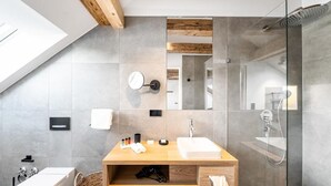 A modern bathroom with a wooden vanity, a glass shower enclosure, and a skylight. - Alte Schule Tiefenbach  (Östringen)