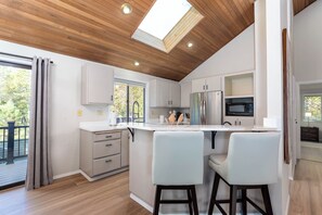Eine moderne Küche mit weißen Schränken, einem Edelstahl-Kühlschrank und einer großen Kochinsel mit Barhocker.