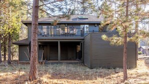A modern two-story house with a balcony, surrounded by trees. - ROCK06 - Luxurious Sunriver Home, Hot Tub (Sunriver)