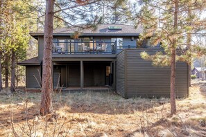 Ein modernes, zweistöckiges Haus mit Balkon, umgeben von Bäumen.