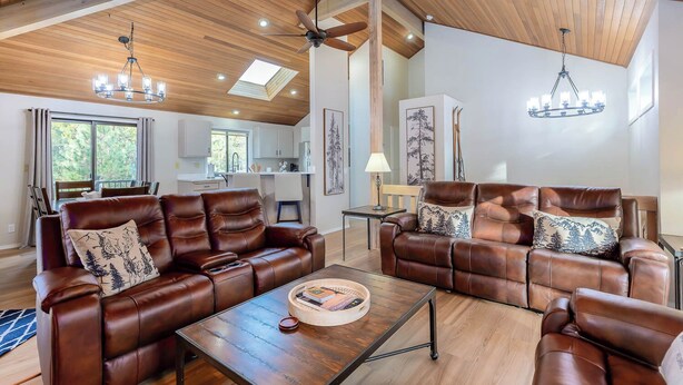 A spacious living room with leather sofas, a coffee table, and a dining area with a kitchen in the background. - ROCK06 - Luxurious Sunriver Home, Hot Tub (Sunriver)