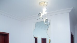 Un comedor con una mesa blanca, cuatro sillas y un espejo grande en la pared.