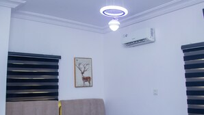 Un dormitorio con cama, mesita de noche, aire acondicionado en la pared y lámpara en el techo.