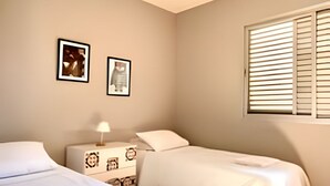 A bedroom with two beds, a ceiling fan, and a window with blinds. - Residencial Liberdade (São Paulo)