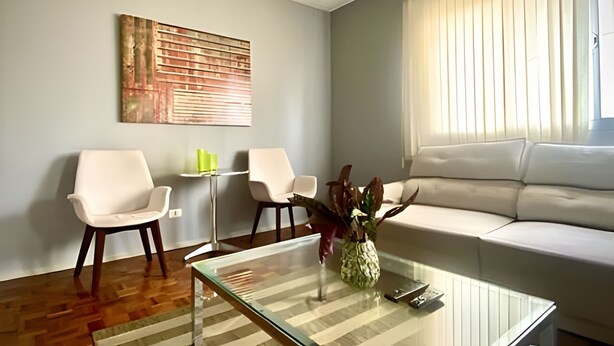 A modern living room with a sofa, two chairs, a coffee table, and a decorative plant. - Residencial Liberdade (São Paulo)