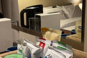 A hotel room with a bed, a coffee machine, and various packaged food items on the table. - Wanderlust Awaits – Your Stylish Retreat in Maadi (Cairo)