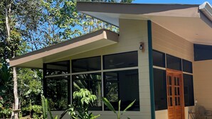 A modern house with large windows, a wooden door, and a concrete pathway leading to the entrance.