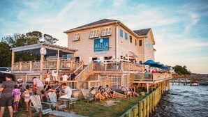 A waterfront restaurant with outdoor seating and a deck extending over the water. - BIS-Duck - 2BR/2BA - Great Pools & Beach! (Duck)