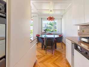 Une cuisine moderne avec un coin repas, un plancher en bois et une vue sur l’extérieur.