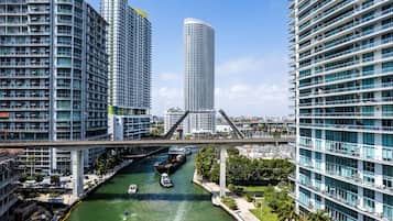 Ein modernes Stadtgebiet mit Hochhäusern, einem Fluss mit Booten und einer Fußgängerbrücke.