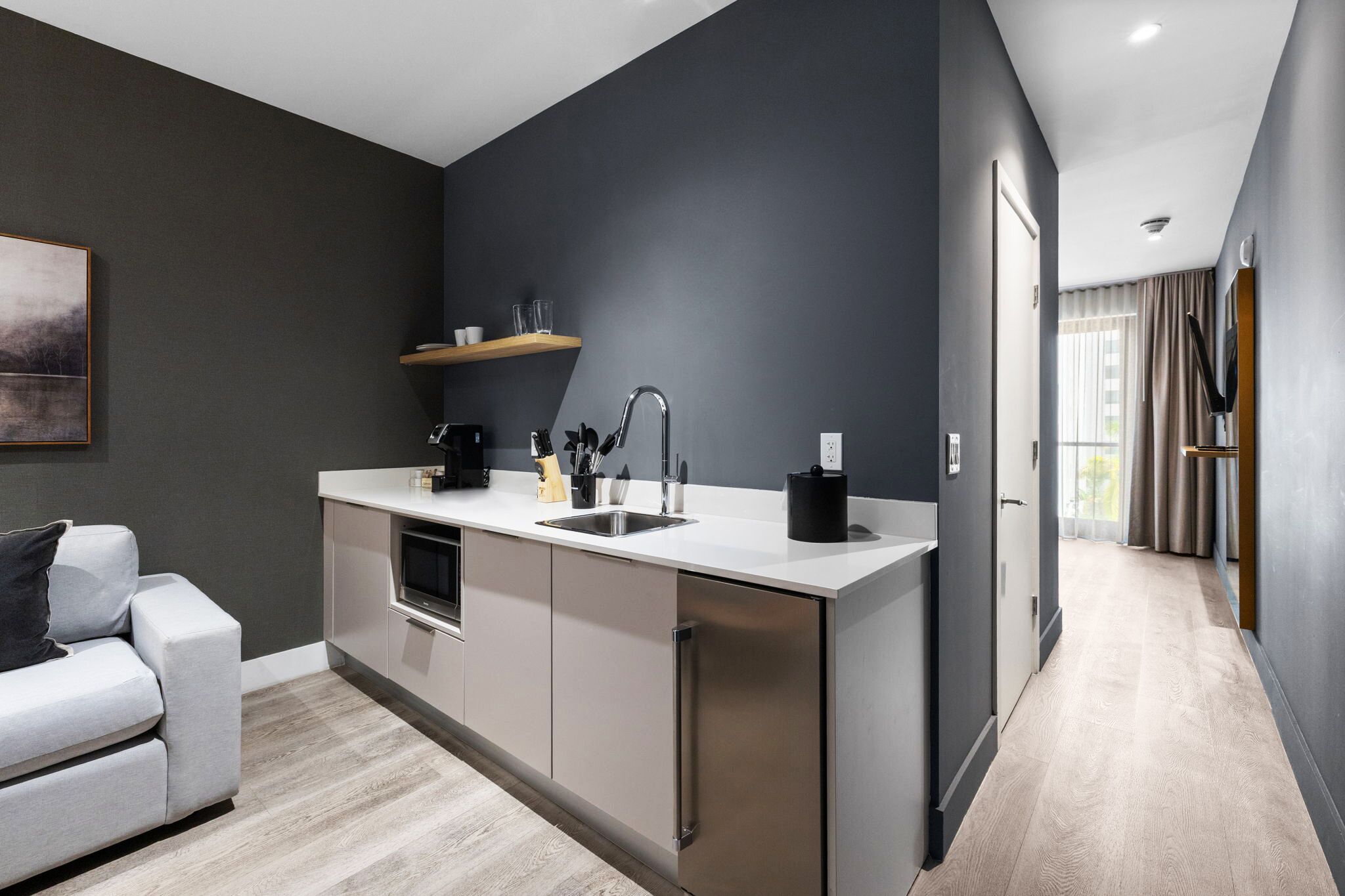 A modern kitchen with a built-in island, stainless steel appliances, and a grey wall.