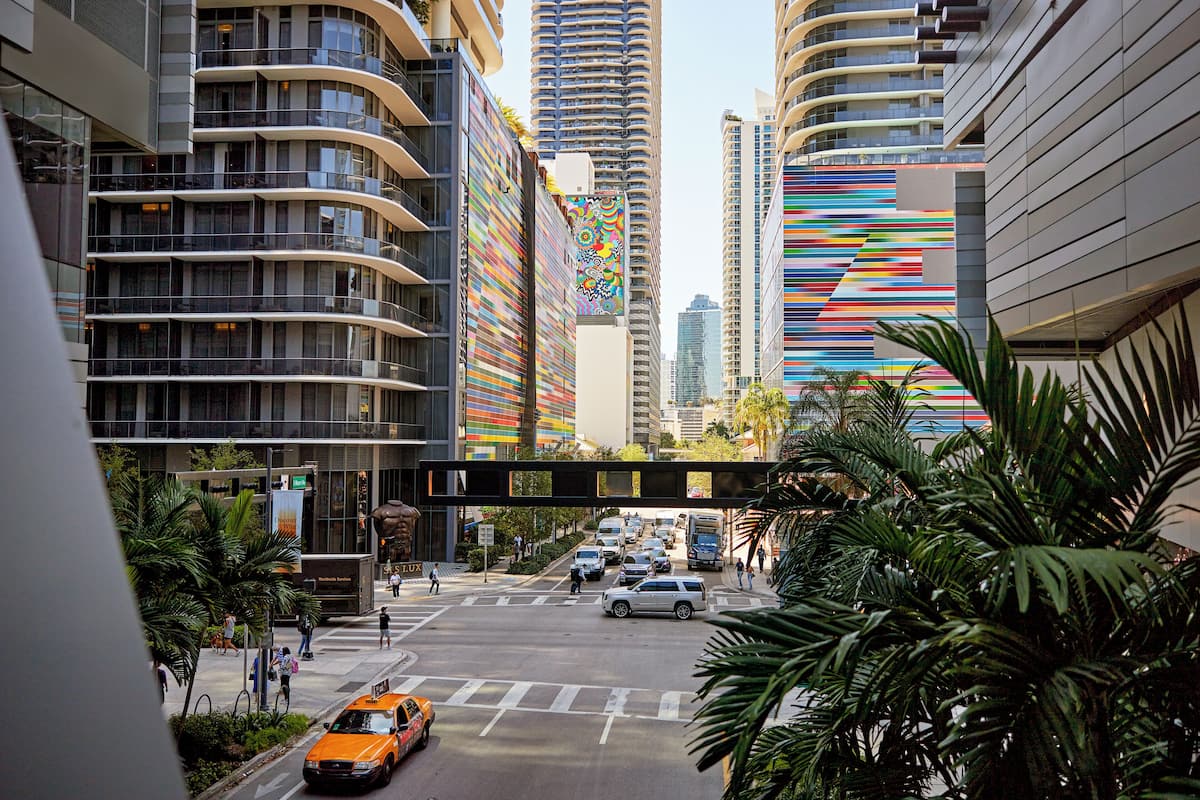 A modern urban street with high-rise buildings, a pedestrian crossing, and a taxi.