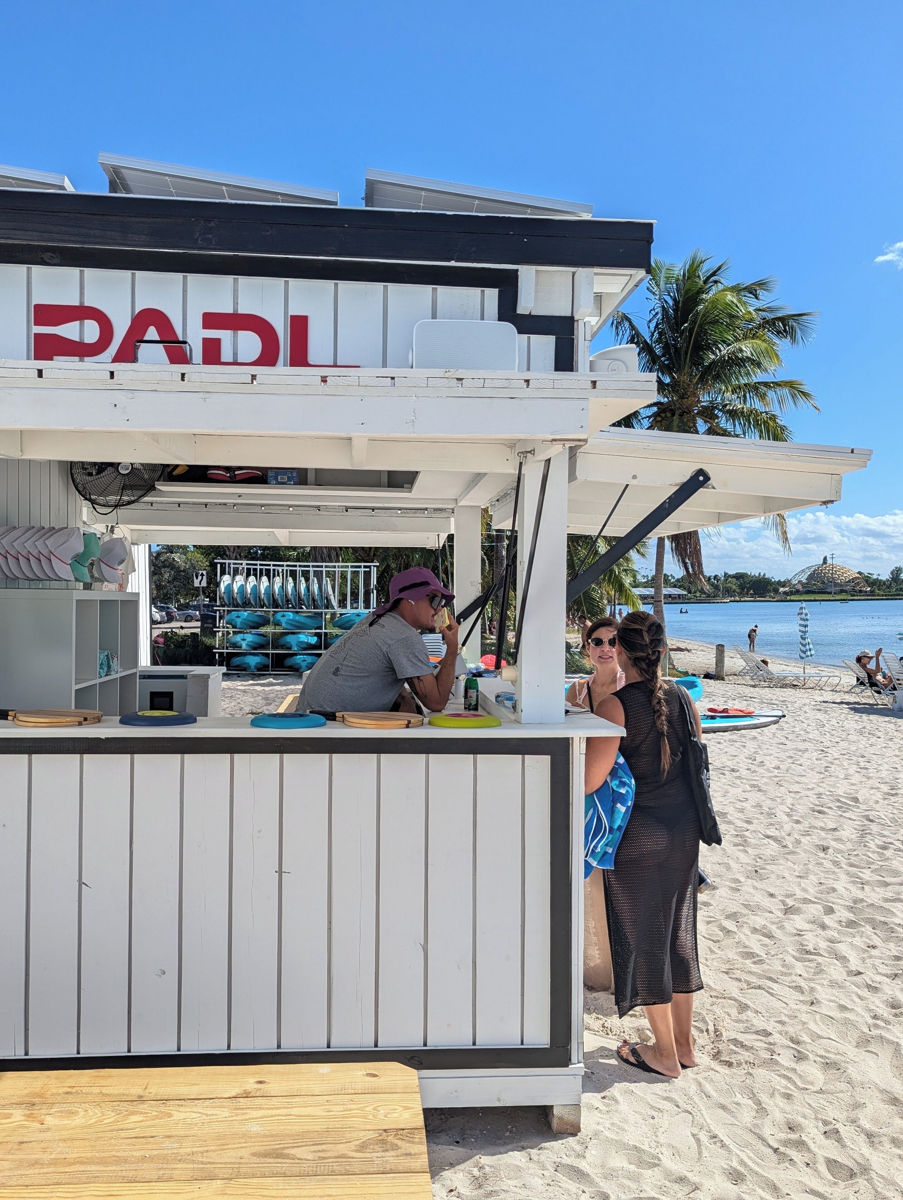 A beachside kiosk with a sign reading "PADI" and a counter with various items.