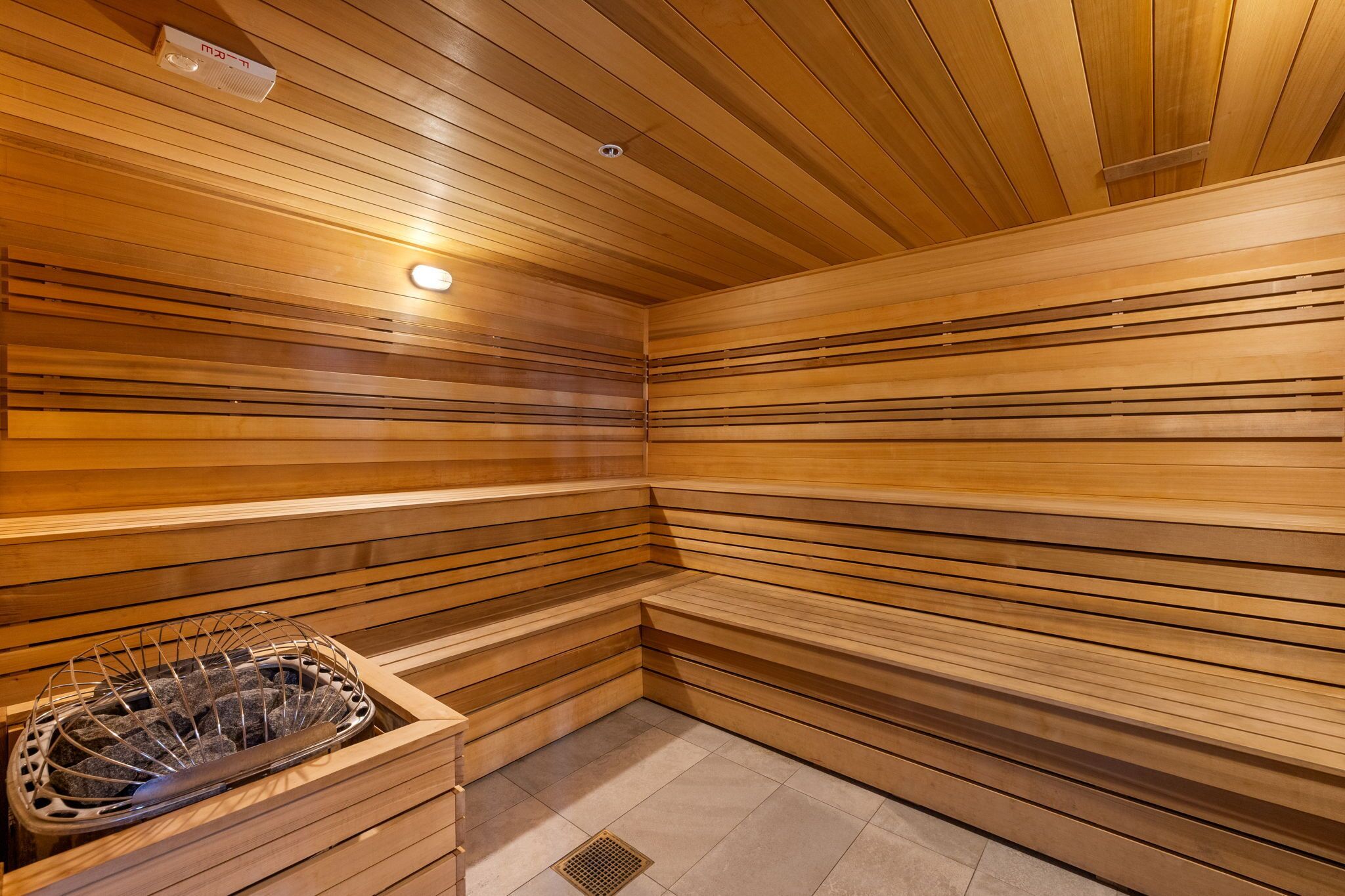 A sauna with wooden slats, a bench, and a metal basin.