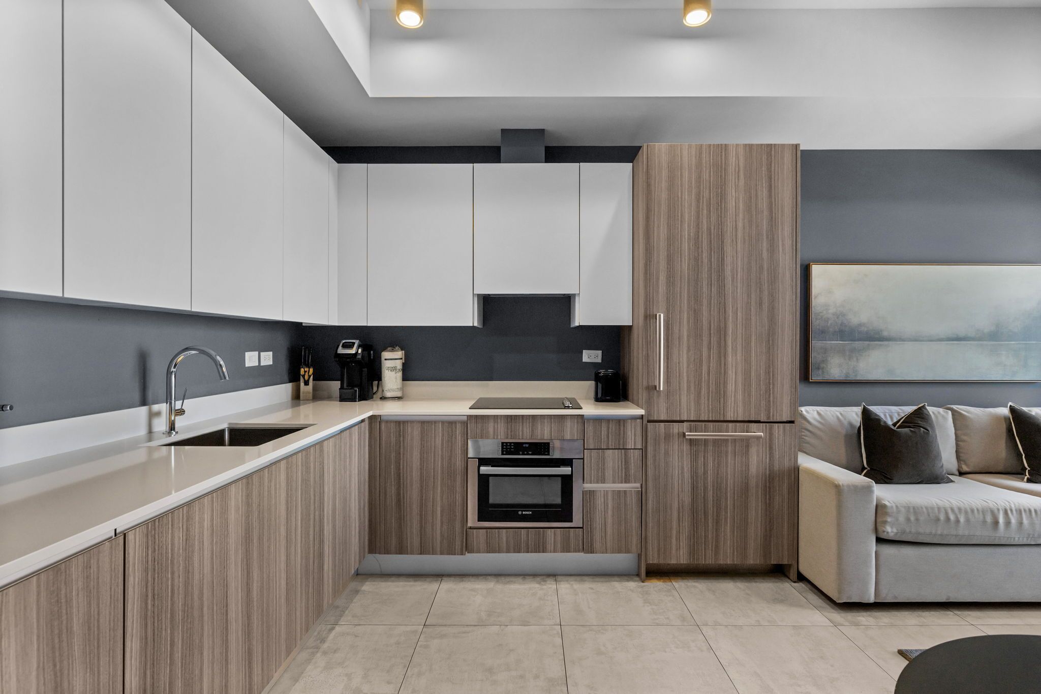 A modern kitchen with integrated appliances, a built-in oven, and a grey countertop.