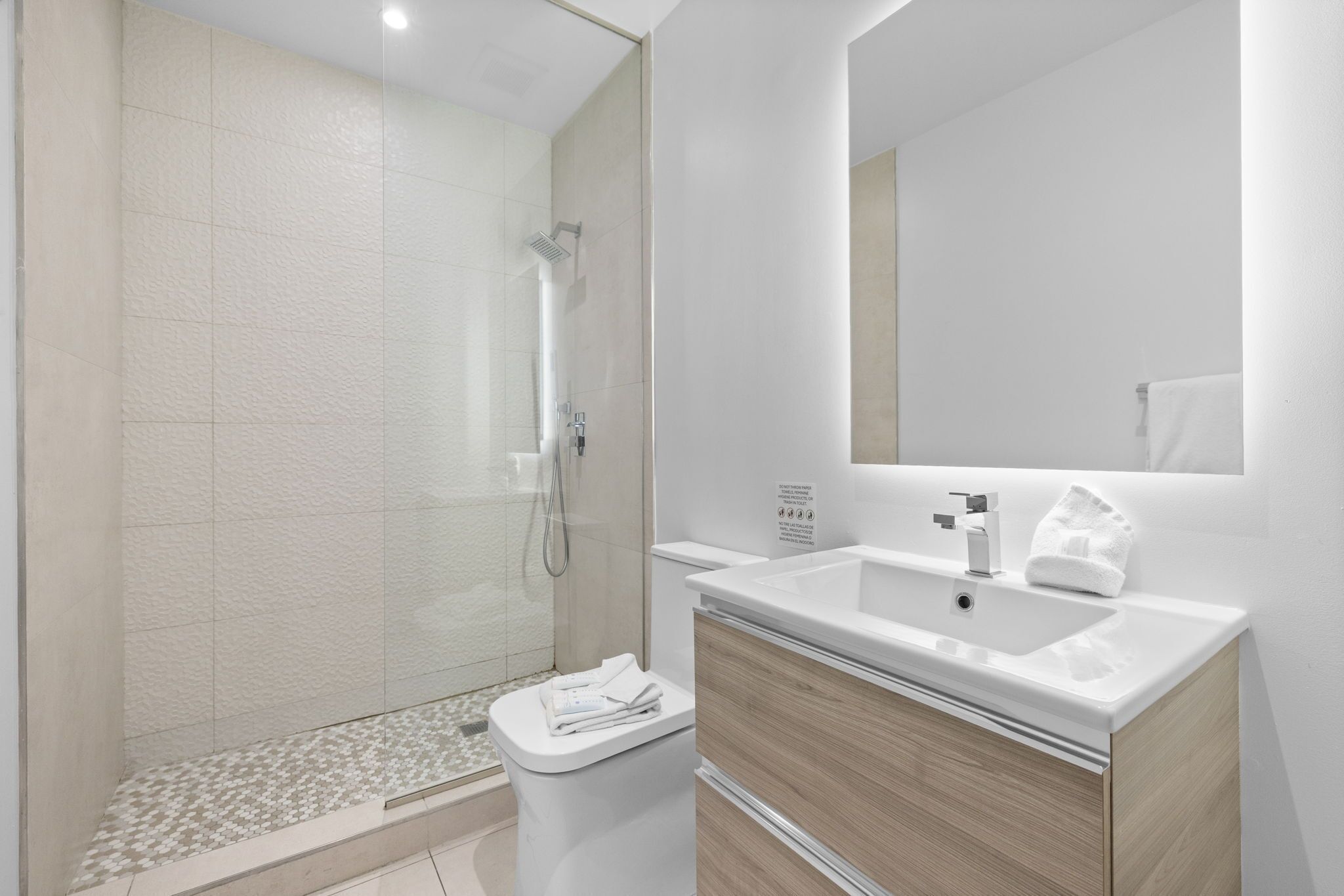 A modern bathroom with a shower, toilet, and sink.