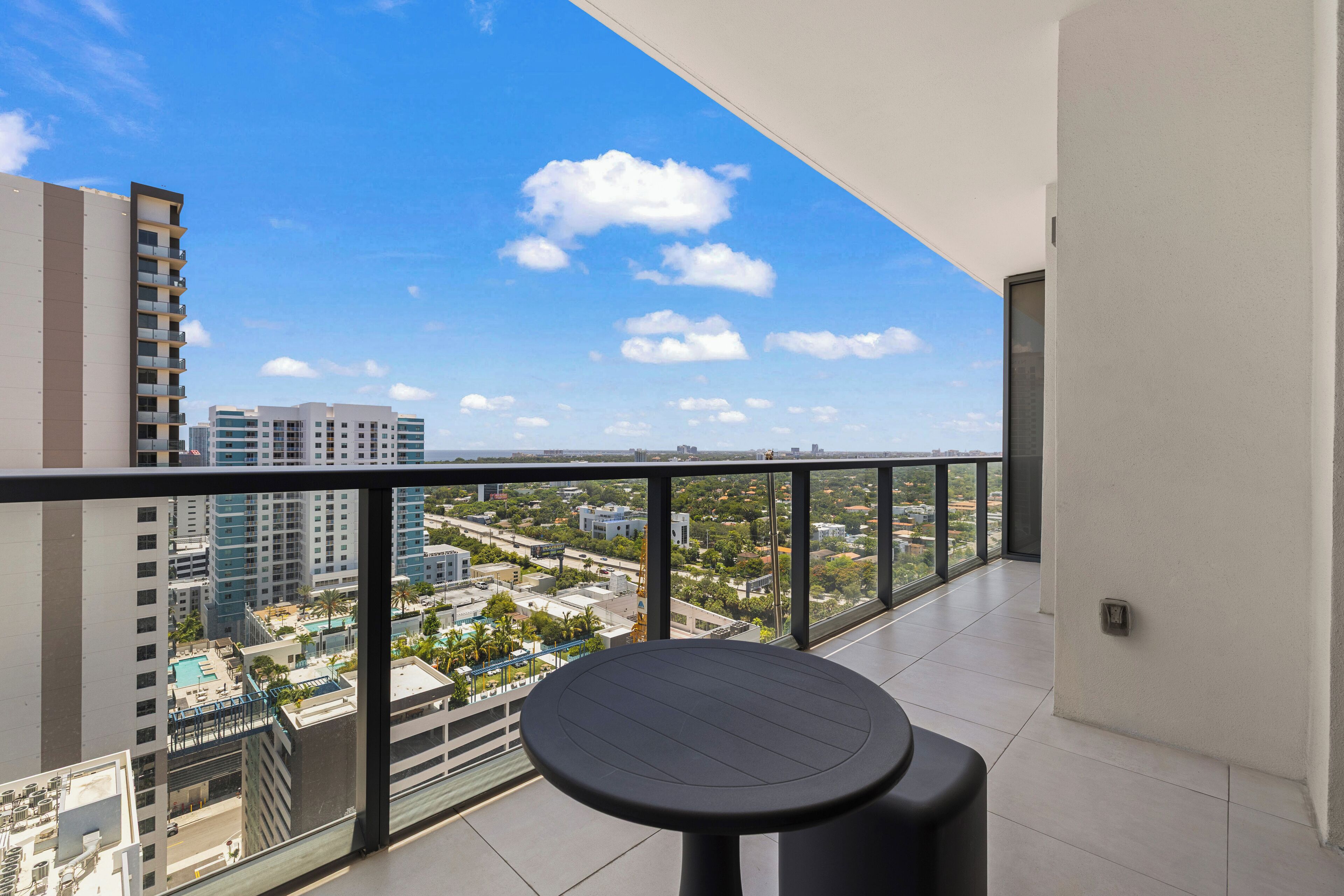 A balcony with a table and chairs, offering a city view.