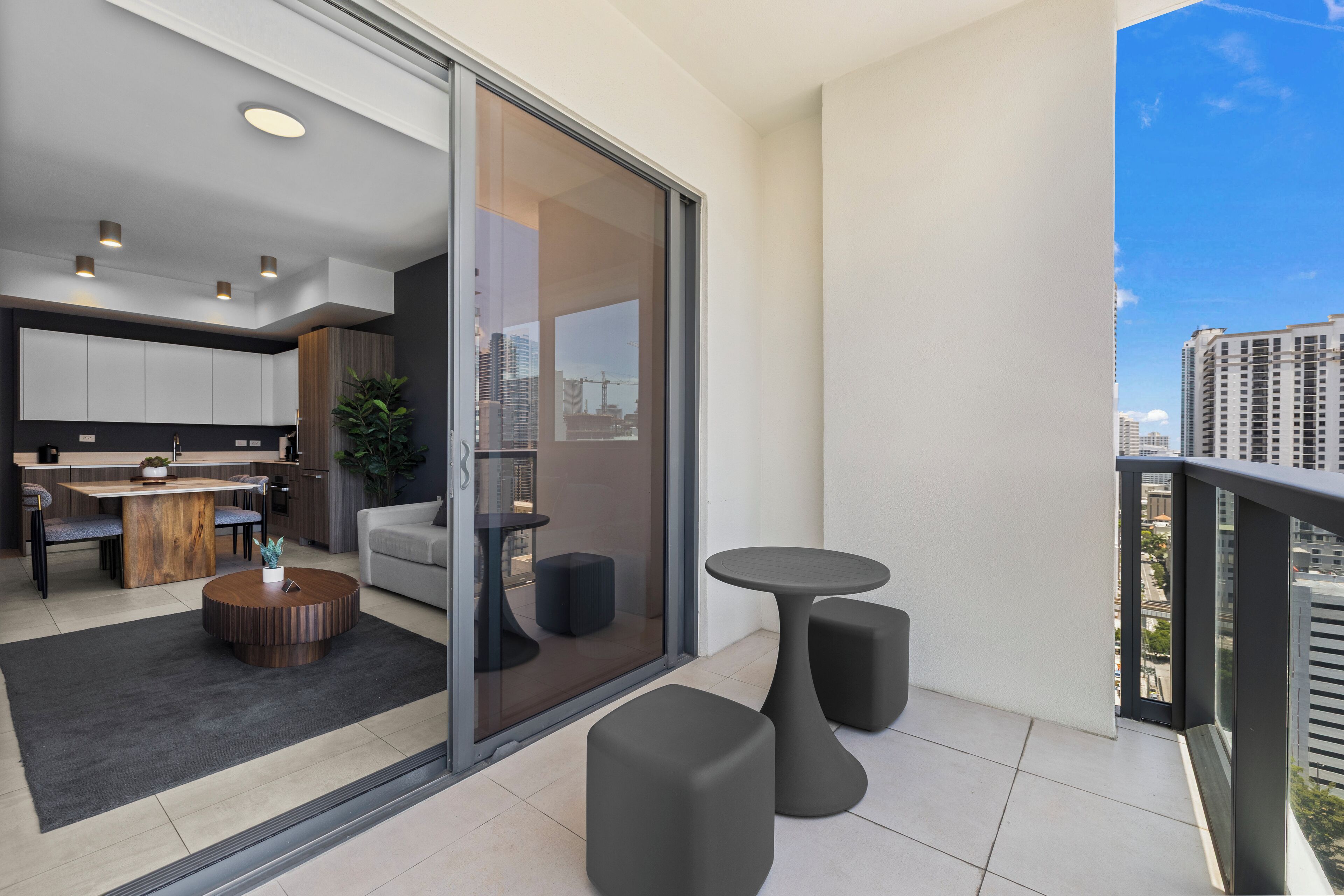 A modern apartment with a balcony, a dining area, and a view of the cityscape.