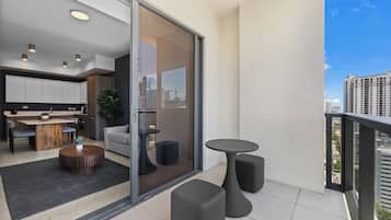 A modern apartment with a balcony, a dining area, and a view of the cityscape.