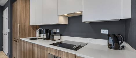A modern kitchen with a built-in stove, a coffee maker, and a kettle.