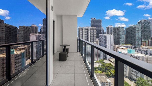 A balcony with a city view, a small table, and a chair. - Brickell Condos by Vibras Concierge (Miami)