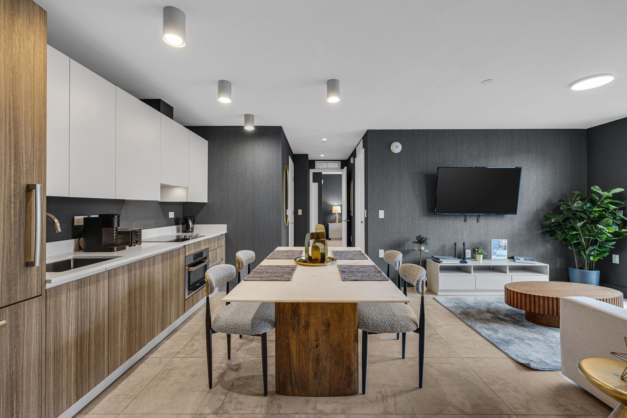 Une cuisine moderne dotée d’un îlot central, d’appareils électroménagers intégrés et d’un téléviseur à écran plat fixé au mur.