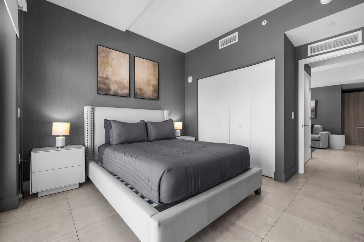 A modern bedroom with a large bed, bedside tables, and a wardrobe.