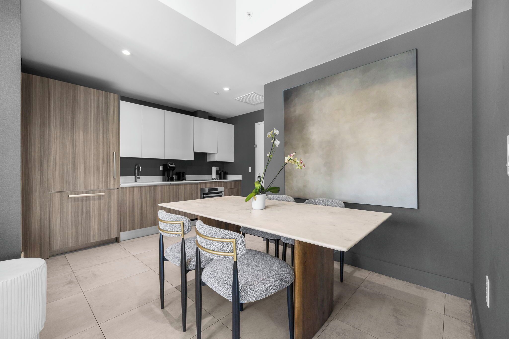 Une cuisine moderne avec un coin repas, comprenant une grande table, des chaises et une plante en pot.
