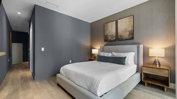 Un dormitorio moderno con una cama grande, lámparas de noche y vistas a un pasillo.